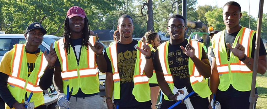 Five African American Male men in safety vests at clean up day showing J sign for Jaguars