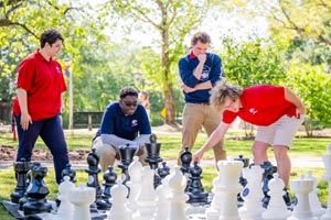 Honors students playing large chess set.