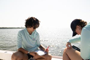 Students taking notes on boat in Marine Sciences.