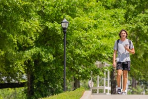 Student walking on campus talking on phone.