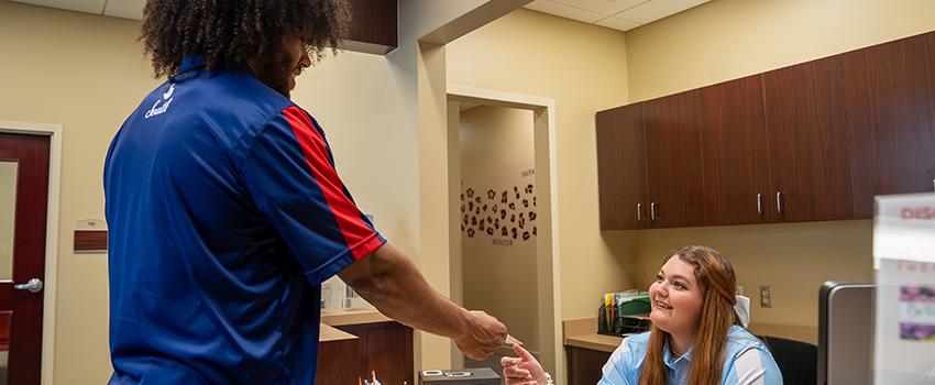 Student worker handing credit card to student purchasing tickets.