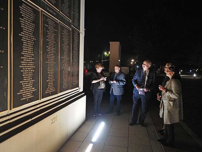 Group talking in front of wall of honor.