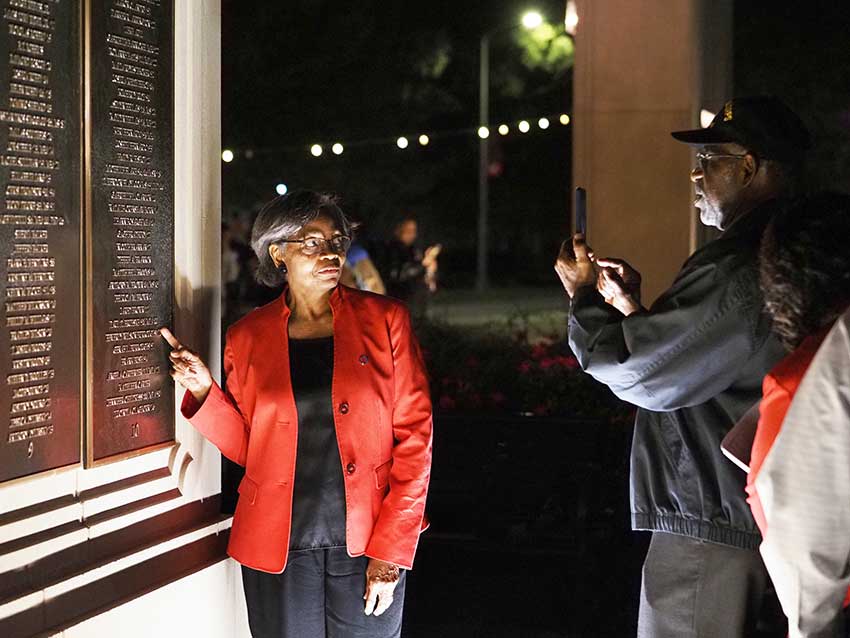 Woman pointing at wall of honor.