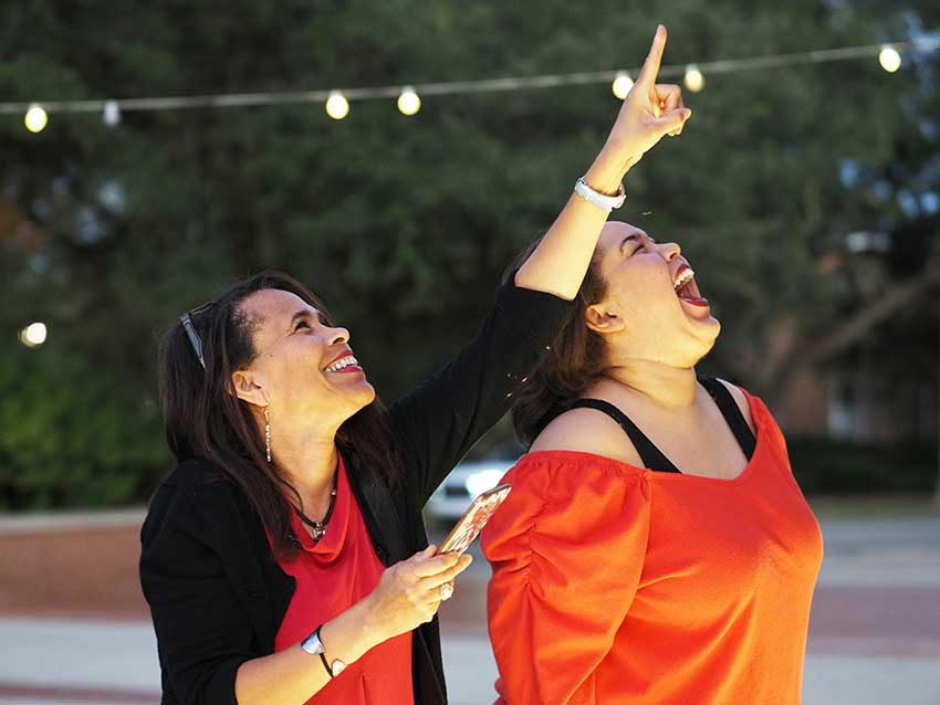 Woman pointing up with another woman looking up.