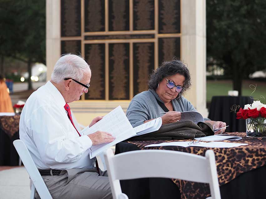 Two people sitting at table in front of tower.