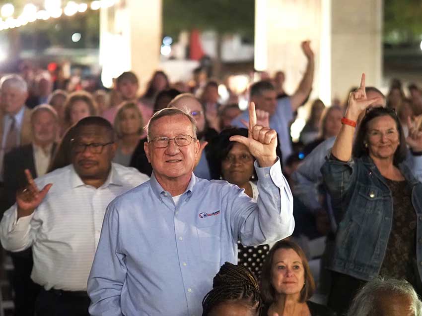 Crowd holding up J sign.