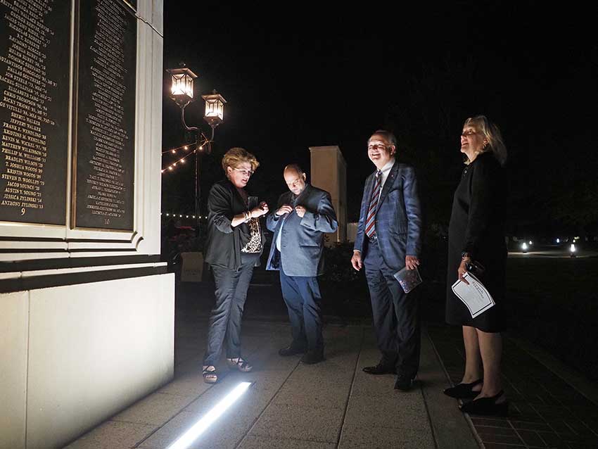 Group talking in front of wall of honor.