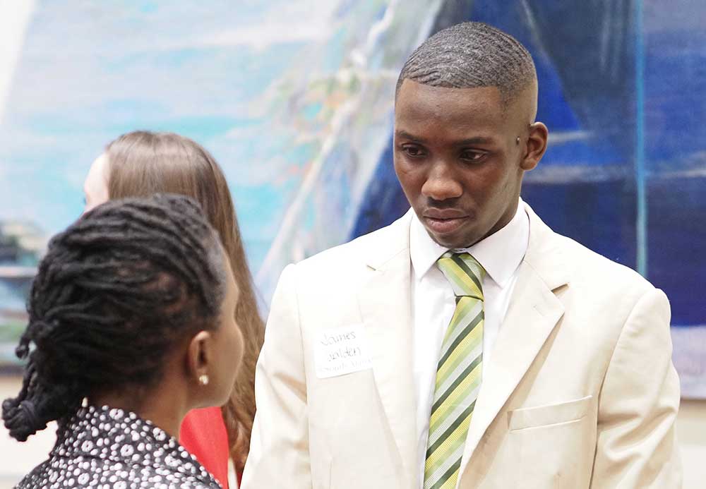 Man in suit and tie talking to woman.