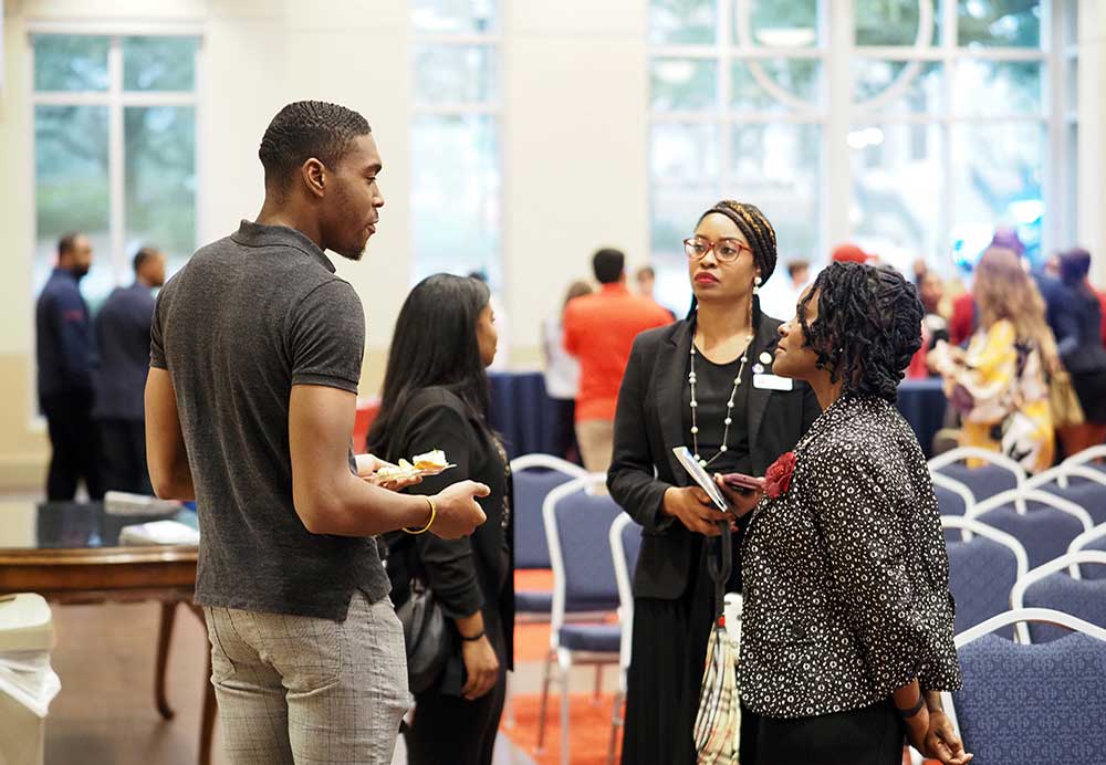 Three people talking at event.