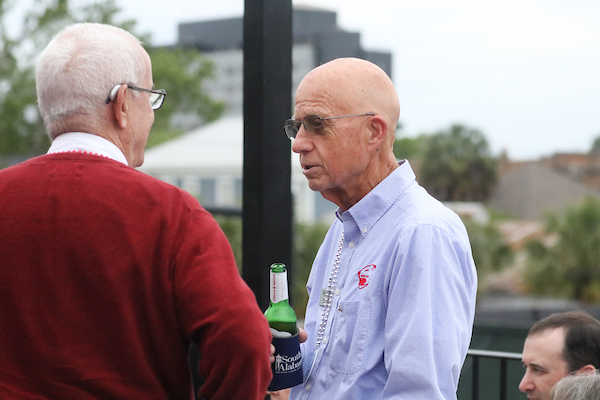 Man holding bottle talking to another alumni.