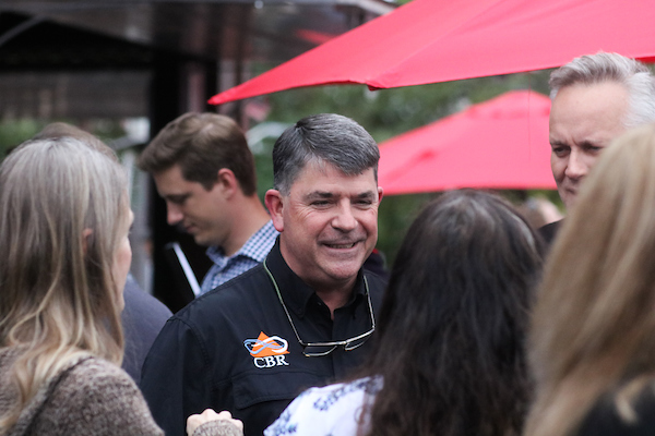 Man in black shirt smiling.