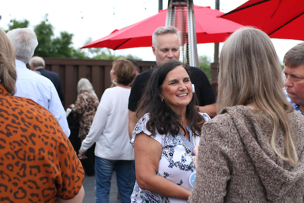 Woman in flowered shirt talking at event.