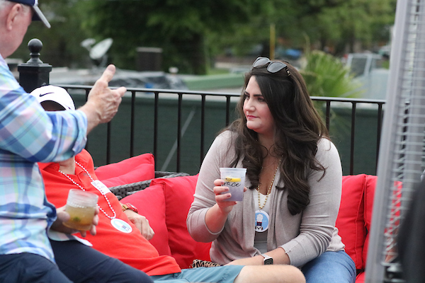 Woman holding drink listening to someone talk.