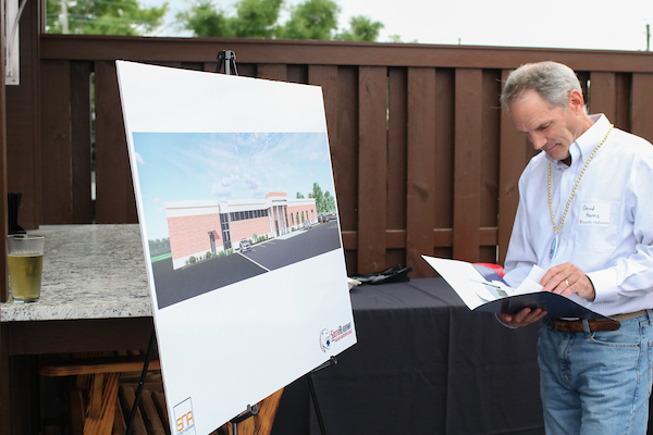 Man looking at book standing in front of rendering of new marching band building.