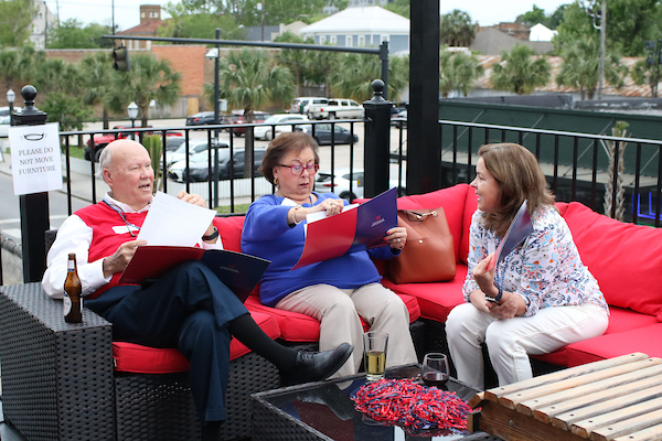 Two people holding books talking sitting on couches on outsoar patio.