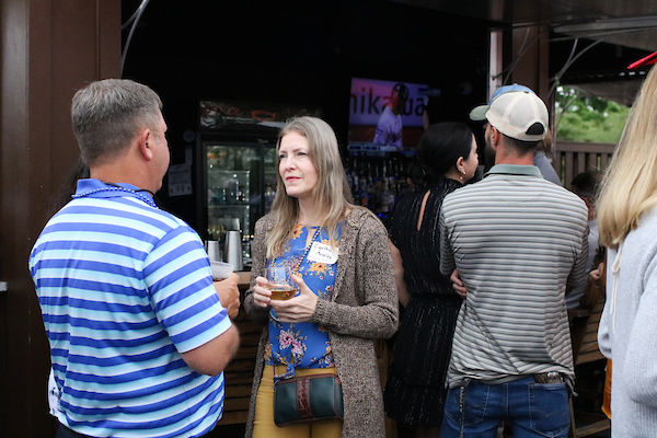 Woman in flowered shirt and sweater listening to someone speak.