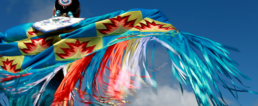 Native American multi color garb with sky in background.