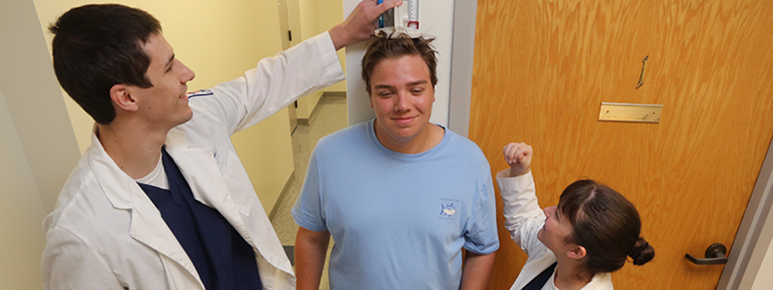 Patient getting his height measured by nurses.