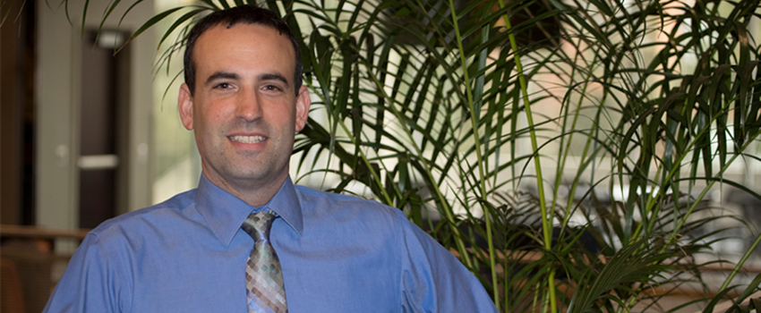 Dr. David Meola in front of a plant.