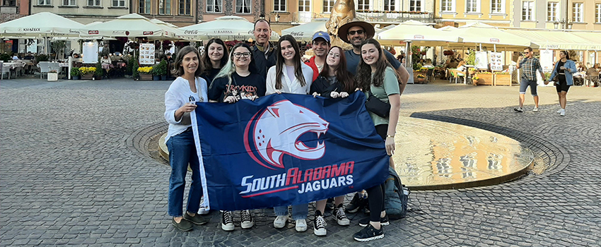 Dr. David Meola with students holding a Jag flag.