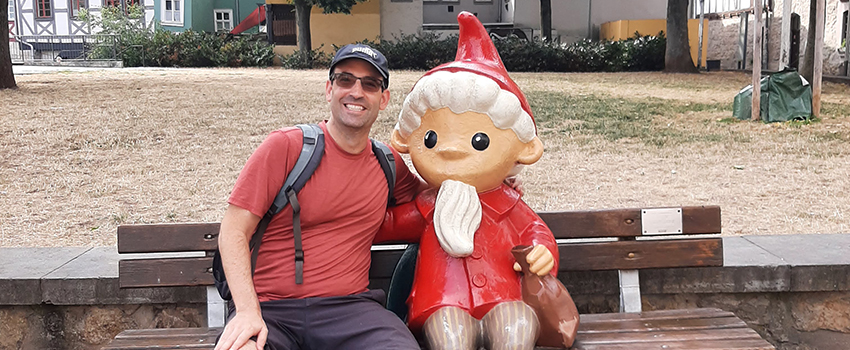 Dr. David Meola sitting on a bench with a statue.