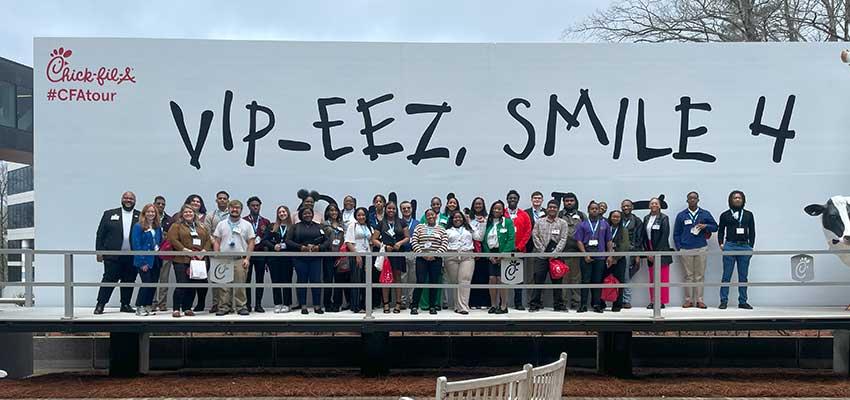 Group of students in front of Chick fil a sign.