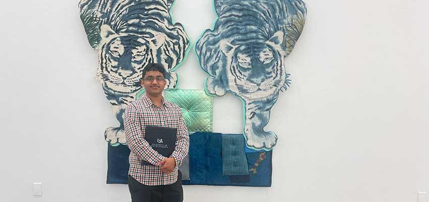 Male student in front of tiger art on wall.