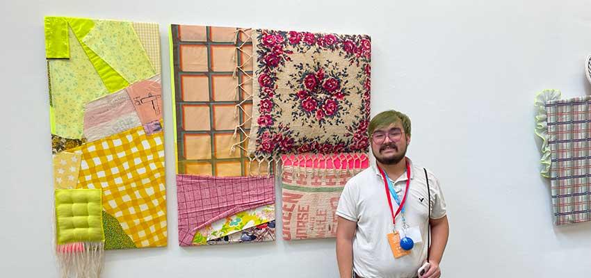 Male student in front of art on wall.