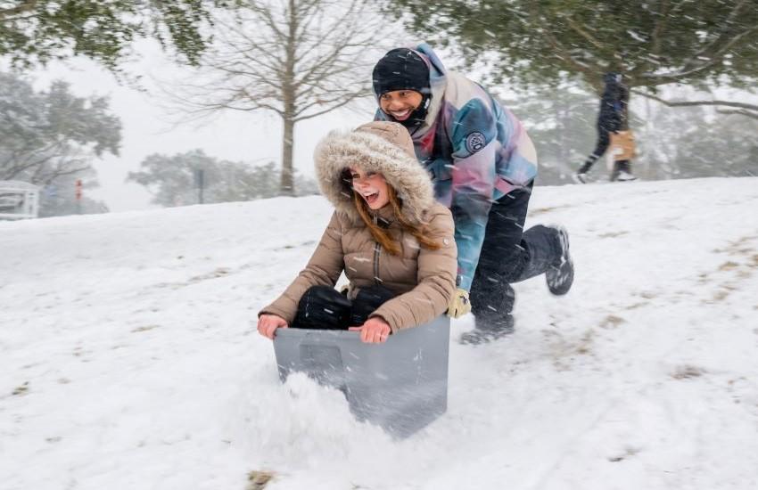 Student pushing another student in box in the snow.