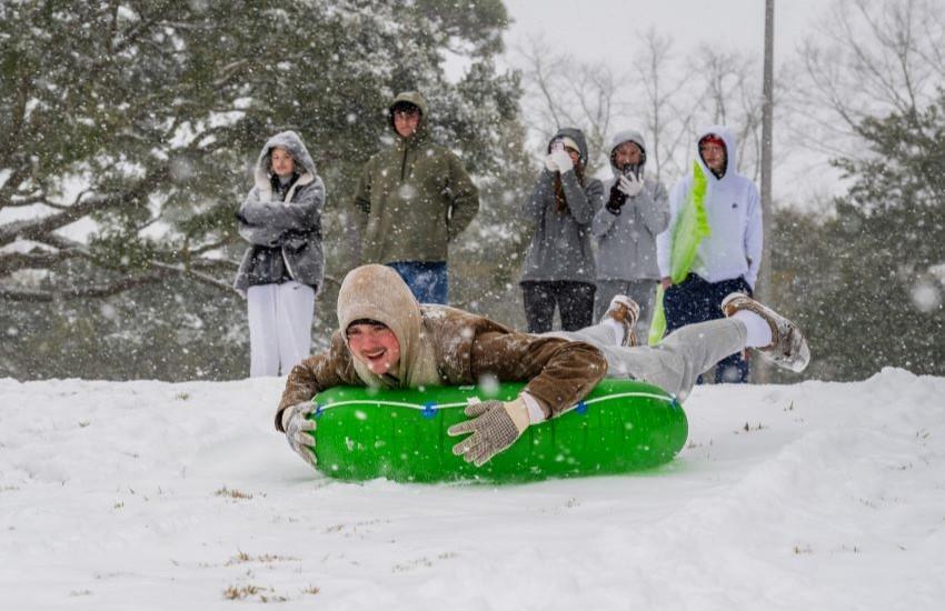 Student laying on tube sliding down hill.