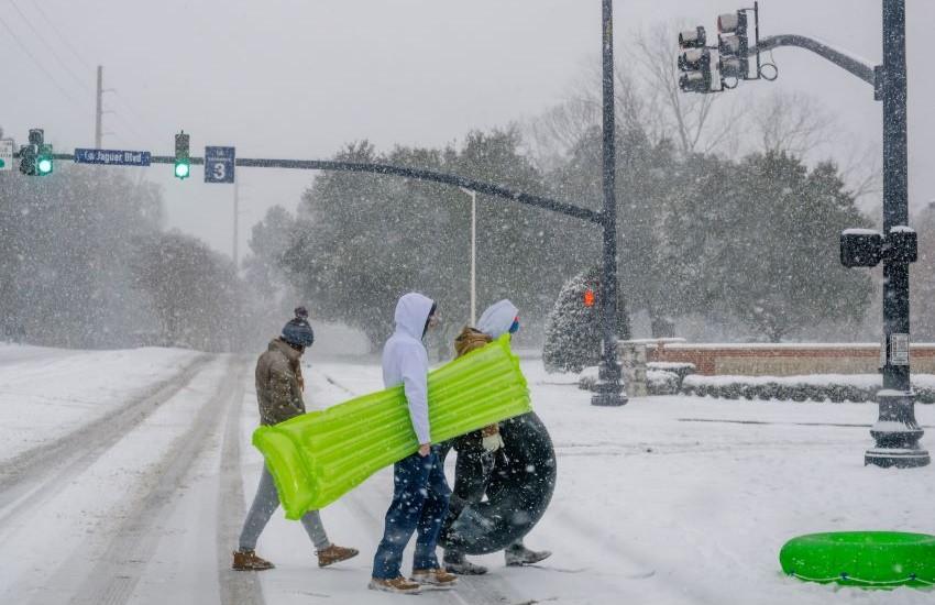 Students carrying floats in the snow to sled on.