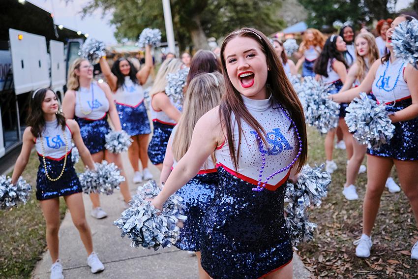 Cheerleader smiling with her pom poms during Mardi Gras Celebration