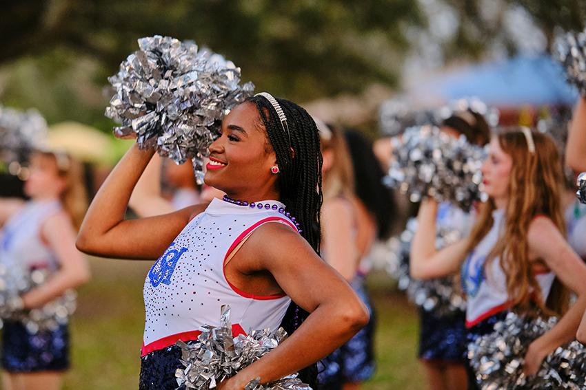 Cheerleader smiles while raising her pompoms 