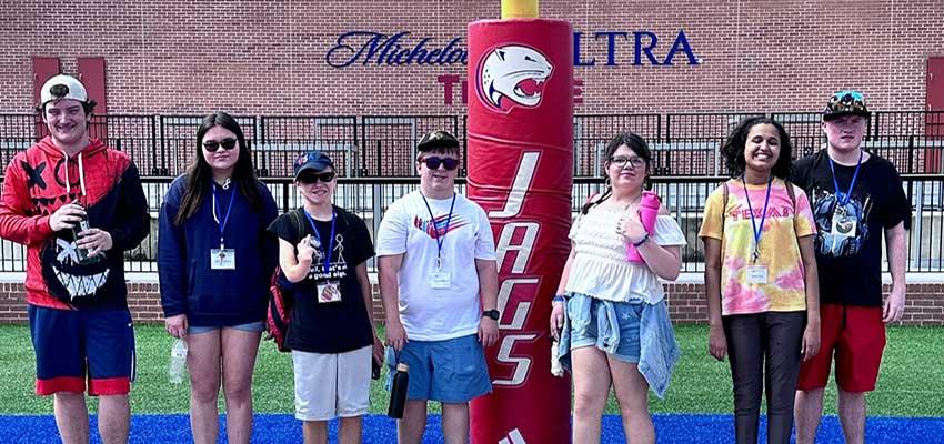 Pep camp students on football field in front of goal post.