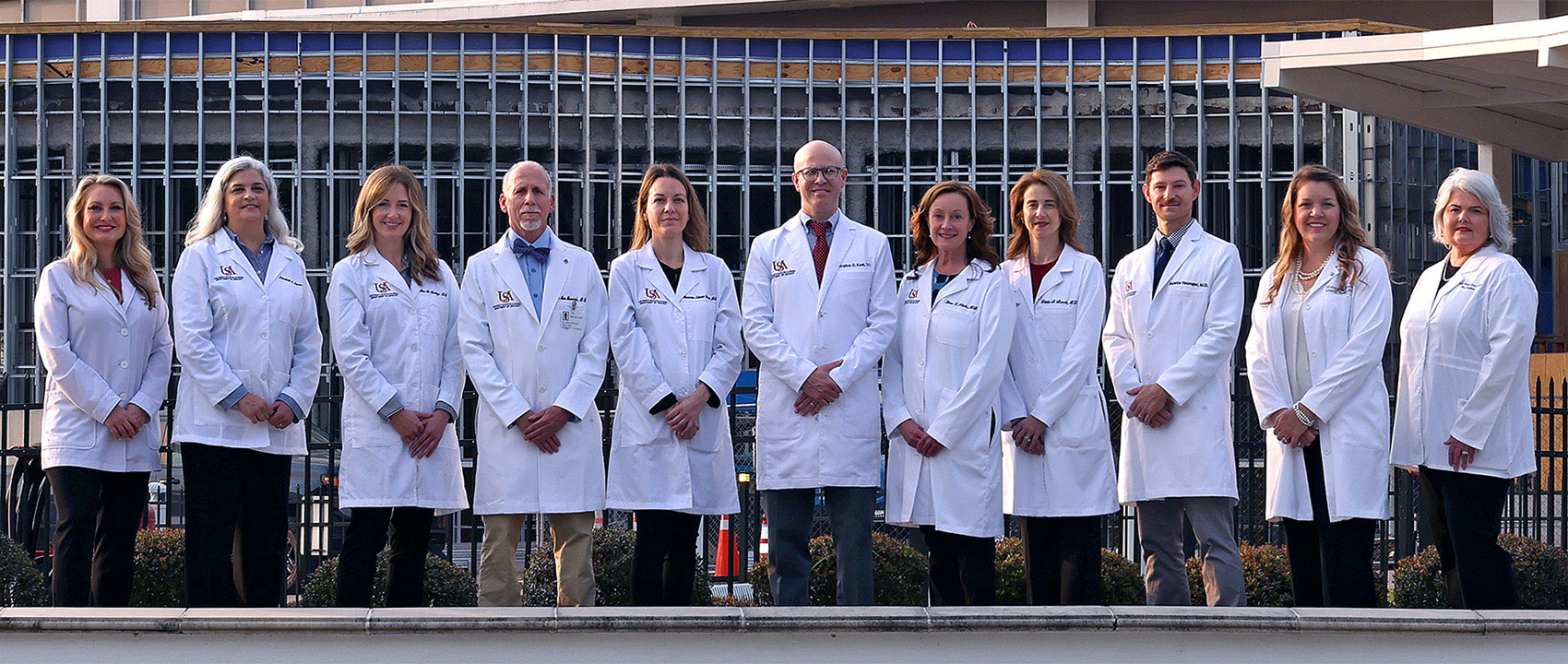The faculty of the USA Department of Urology stand in front of USA Health University Hospital.