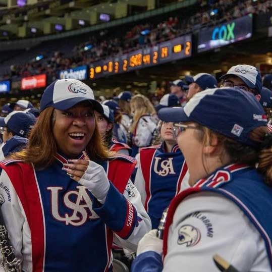 Mkali talking to another band member at a football game in uniform.