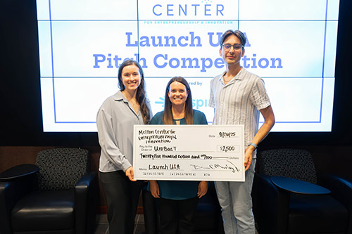 Three students holding check in competition.