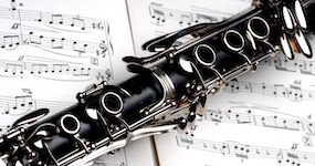 Pictured is a graphic featuring a clarinet laying on top of a music score.