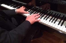 A closeup of a pianists hands are pictured playing a Steinway grand piano.