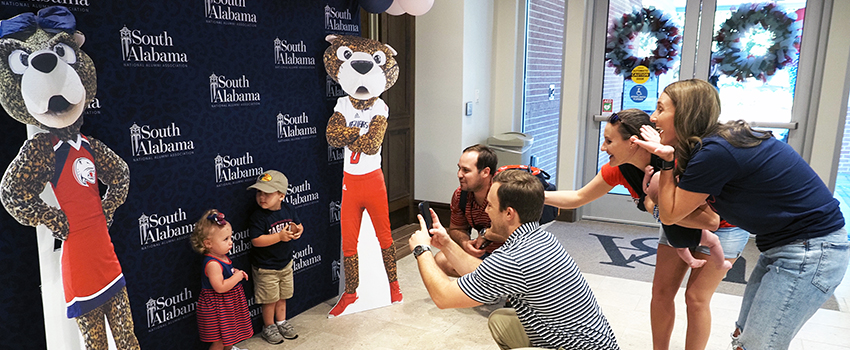 Alumni taking images of their children with cutouts of Southpaw and Ms. Pawla.