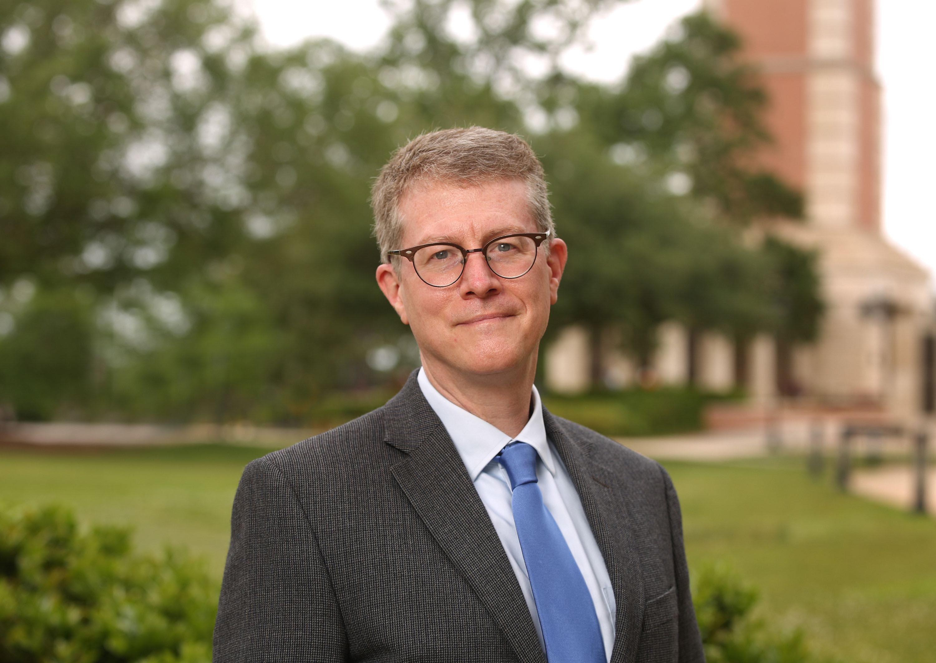 photo of Dr. John Halbrooks standing in front of the Moulton Tower