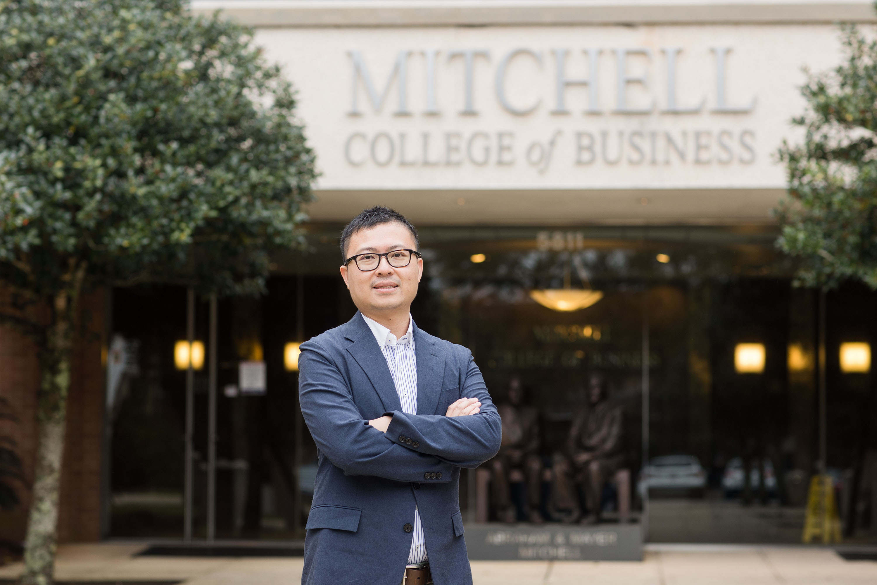 photo of Dr. Ray Wu standing with his arms crossed in front of the Mitchell College of Business