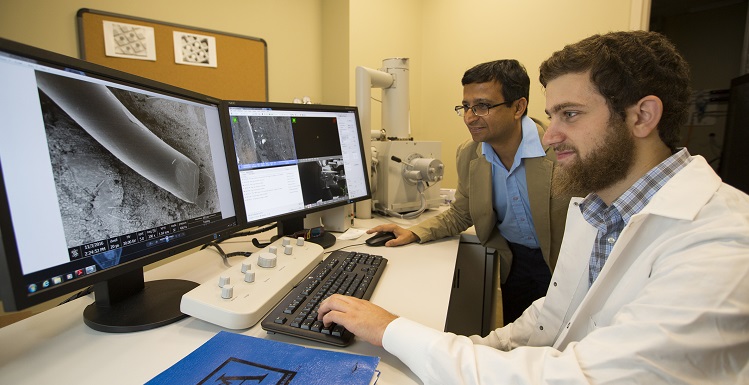 Engineering student Yousef Omar, right, and Dr. Sumit Arora, instructor in the College of Engineering's Core Facility, examine a silver wire magnified 200 times with the University's scanning electron microscope.  Silver nanoparticles are a key ingredient in their research efforts regarding sunscreens and other biomedical applications.