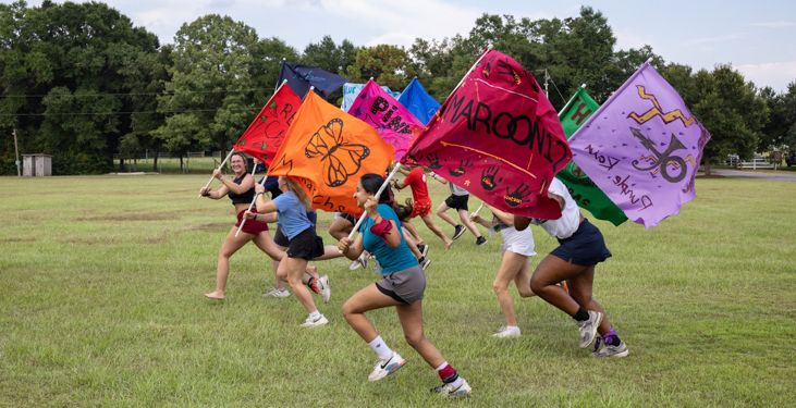 Members of each of the 12 groups of students carry the colorful flags they made at the Honors College retreat. The flags will eventually hang in the Bethel, the Honors College headquarters.