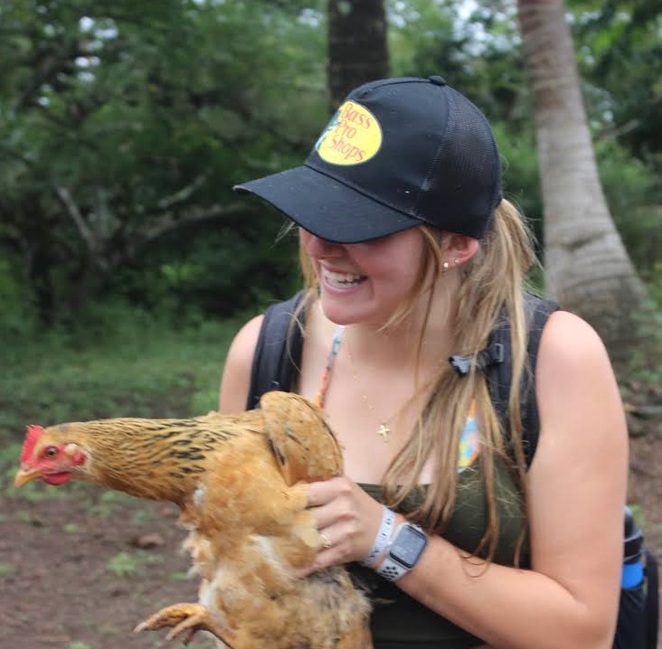 Female student holding a chicken and smiling in Ecuador and Galapagos